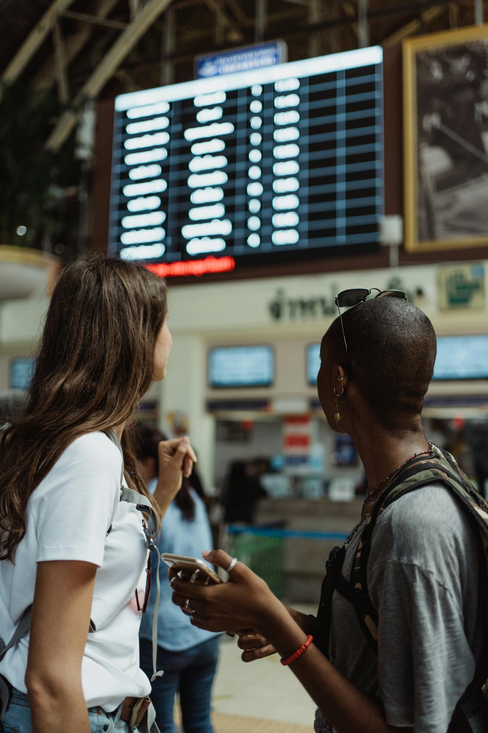 two passengers at the airport with checking the board